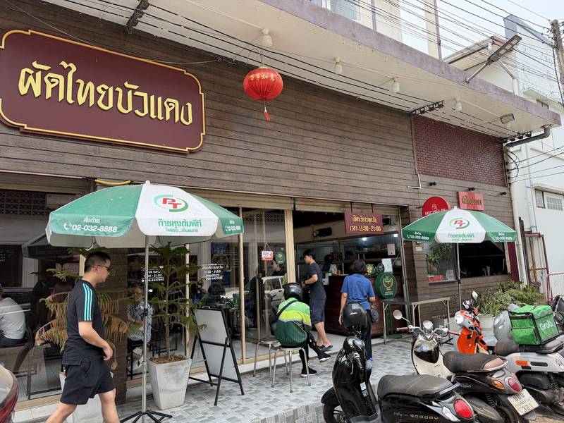 หน้าร้านผัดไทยบัวแดง ป้ายชื่อร้าน ร่ม และโคมแดง
