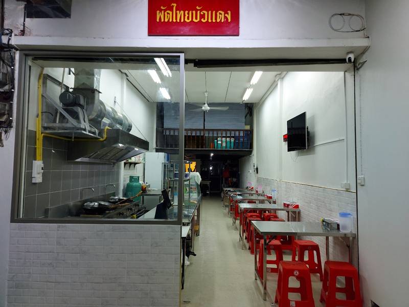 ภายในร้านผัดไทยบัวแดง ครัวกระจกและเก้าอี้สีแดง